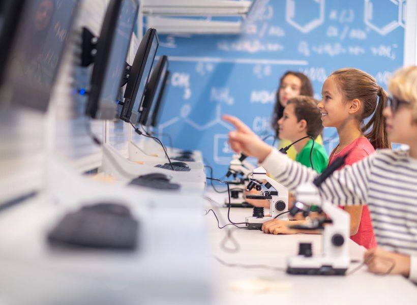 Smart school. Boys and girls standing sideways to camera looking intently at electronic boards in chemistry class